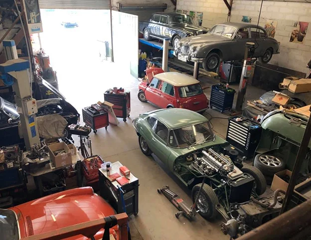 Garage automobile rempli de voitures classiques en réparation, outils dispersés à Veigné près de Tours en Indre-et-Loire 37