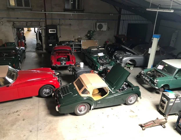 Atelier rempli de voitures classiques en réparation, avec capots ouverts à Veigné près de Tours en Indre-et-Loire 37