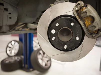 Disque de frein de voiture et étrier rouillé, avec roues et élévateur d'atelier en arrière-plan à Veigné près de Tours en Indre-et-Loire 37